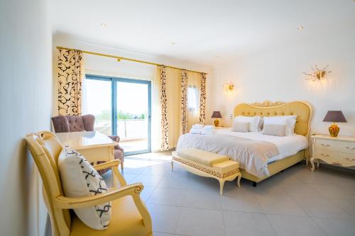 een slaapkamer met een groot bed en een stoel bij Ocean View Villa in Boliqueime