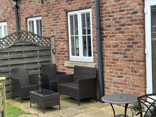 a group of chairs and tables in front of a brick building at Spoonbill Cottage in Filey