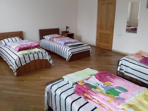 three beds in a room with wooden floors at Art House Hostel Aleksandr in Kutaisi