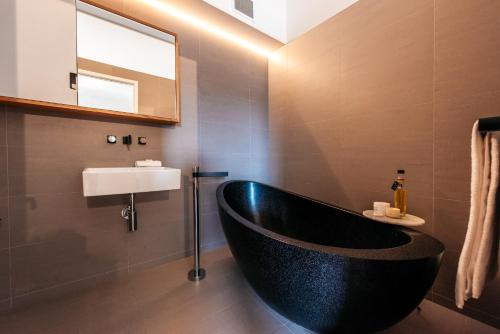 een badkamer met een zwart bad en een wastafel bij Oneroa Beach Apartment in Blackpool
