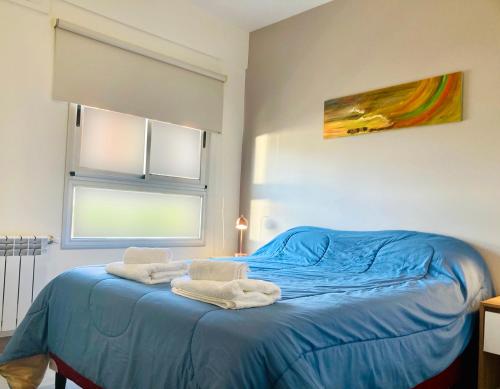 Un dormitorio con una cama azul con toallas. en Departamento 1 dormitorio a estrenar en Salta