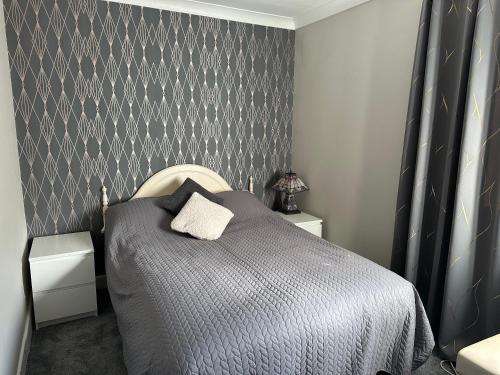 東科維斯的住宿－Remarkable 3-Bed House in East Cowes，一间卧室配有一张带灰色墙壁的床