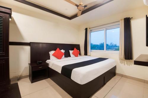 Un dormitorio con una cama con almohadas rojas y una ventana en Capital O Hotel Alfa, en Vijayawāda
