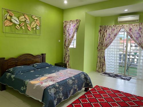 a bedroom with green walls and a bed and a window at Makmur homestay in Taiping
