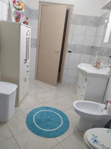 a bathroom with a toilet sink and a blue rug at Light Blue Room in Scordia