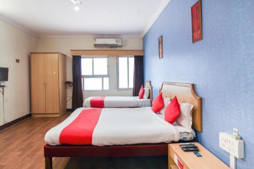 OYO Luxury Villas Near Begumpet Airport في Ameerpet: غرفة نوم بسريرين ومخدات حمراء وبيضاء