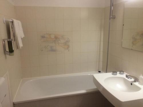 a bathroom with a white tub and a sink at Anne De Beaujeu in Gien