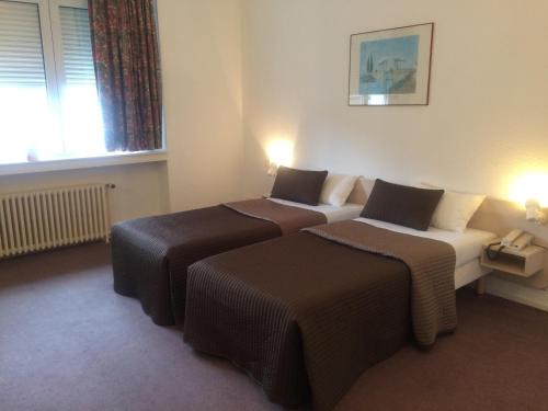 a hotel room with two beds and a window at Anne De Beaujeu in Gien