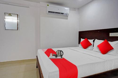 um quarto com uma cama com almofadas vermelhas e brancas em Sai Krishna Residency em Vijayawada