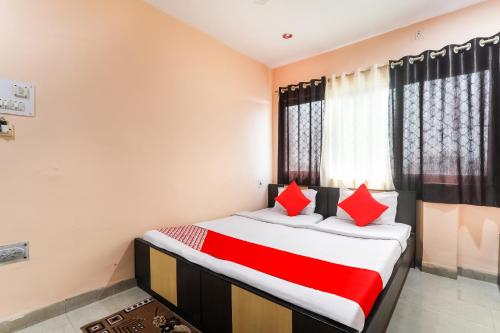 a bedroom with a large bed with red pillows at Hotel Priyal in Chās