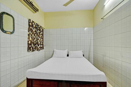 a bed in a room with white tiles at OYO 86379 Dream Palace Guest House Near Marina Beach in Chennai