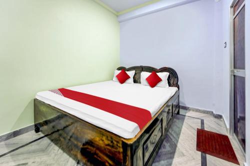 a bedroom with a bed with red and white pillows at Hotel O Laxmi Marriage Hall Restaurant And Guest House in Islāmpur