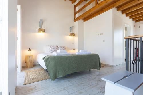 a white bedroom with a bed with a green blanket at Mood Lodging - Óbidos in Óbidos