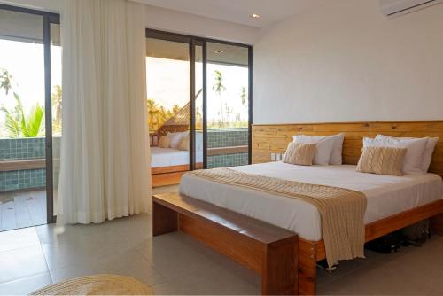 a bedroom with a large bed and a balcony at Kanui Garden Milagres in São Miguel dos Milagres