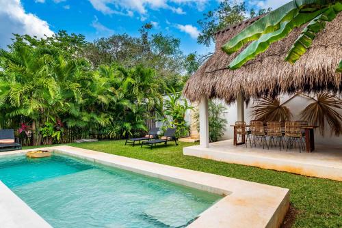 a villa with a swimming pool and a thatch roof at Villa Ek'Balam & Villa Flamingo, Luxury Villas, Private Pool, Private Garden, Jacuzzi, 24h Security in Tulum