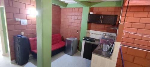 uma pequena cozinha com um sofá vermelho num quarto em Mi pueblo natal Aptos y habitaciones em Necoclí