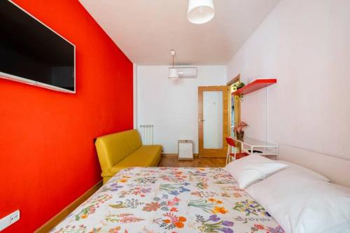 a bedroom with a bed and a tv on a red wall at ESPECIAL para GRUPOS a 3 paradas del metro Atocha in Madrid