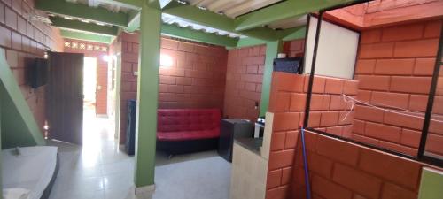 uma casa de banho com um banco vermelho numa parede de tijolos em Mi pueblo natal Aptos y habitaciones em Necoclí