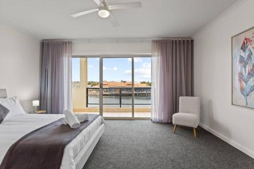 a bedroom with a bed and a window and a chair at Waterfront Townhouse - Picturesque Marina Views in Port Lincoln