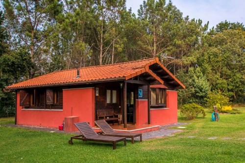 a small red house with a bench in the grass at La Ardilla in Oviñana