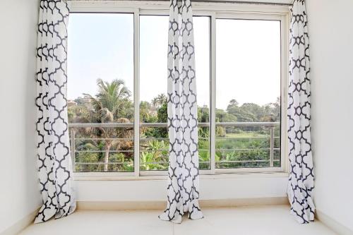 an empty room with two windows with curtains at OYO Home Hotel Sea Prince Suites in Dona Paula