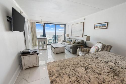 a living room with a couch and a tv at Island Winds East 308 by ALBVR - Beautifully renovated beachfront condo & steps away from Hangout & more! in Gulf Shores