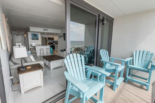 a living room with blue chairs and a table at Island Winds East 308 by ALBVR - Beautifully renovated beachfront condo & steps away from Hangout & more! in Gulf Shores