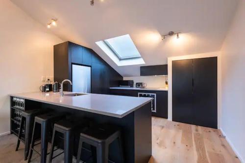 a kitchen with a sink and a counter with stools at Inner City Apartment in Wellington