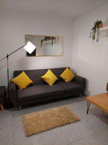 a living room with a black couch with yellow pillows at Уютная 2-х комнатная квартира недалеко от моря in Ashdod
