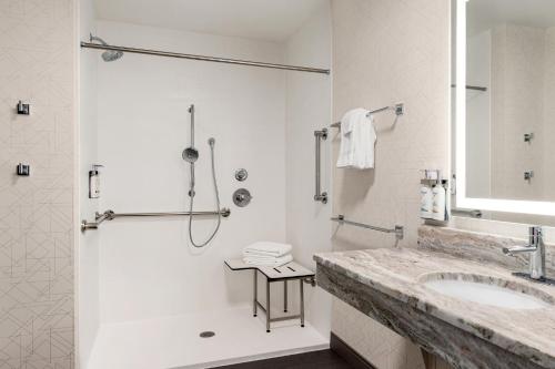 La salle de bains blanche est pourvue d'une douche et d'un lavabo. dans l'établissement Holiday Inn Express & Suites East Greenbush Albany-Skyline an IHG Hotel, à Rensselaer
