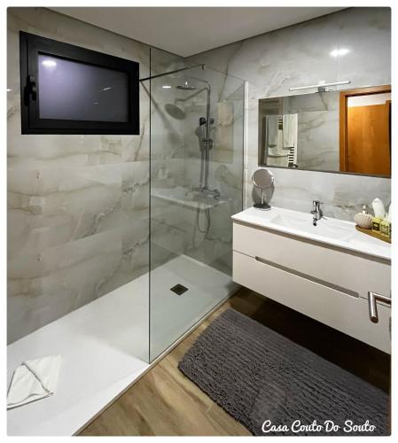 a bathroom with a sink and a tv on the wall at Casa Couto Do Souto in Souto