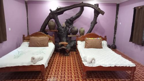 two beds in a room with a tree on the wall at Kakrona Pouk Homestay in Siem Reap