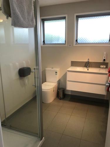 a bathroom with a shower and a sink and a toilet at Coachman Motel in Christchurch