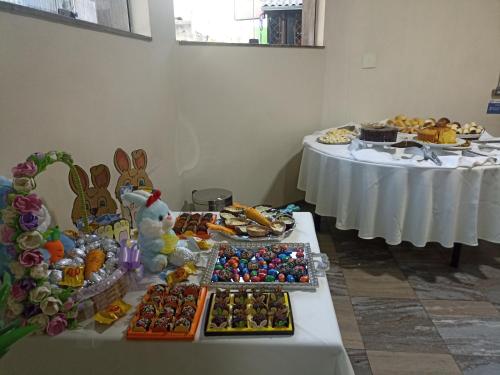 two tables filled with different types of pastries and desserts at Hotel Oscar Econômico Montes Claros in Montes Claros