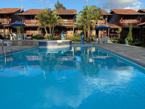 a pool at a resort with blue water at Casa aconchegante e equipada em Gravatá in Gravatá