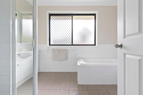 a white bathroom with a window and a tub and a sink at Large seven bed house in Jesmond