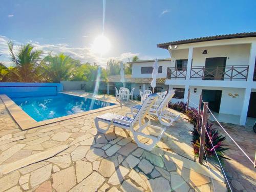 a patio with two chairs and a swimming pool at Casablanca Beira Mar, 5 Suítes, Praia Tabuba AL in Barra de Santo Antônio