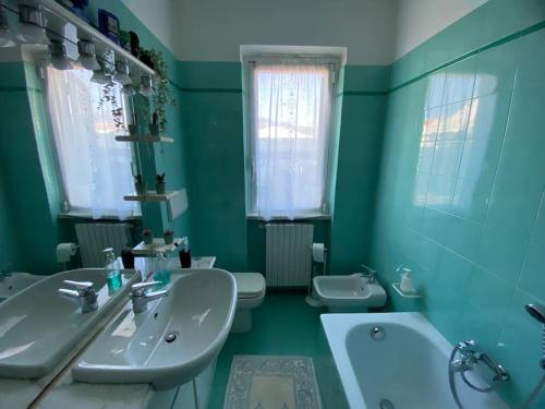 a green bathroom with two sinks and a tub and two toilets at Villa Adriana. Villetta a due passi dal mare in Massa