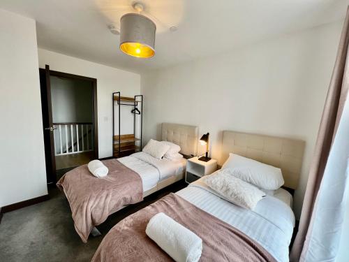 a bedroom with two beds and a lamp in it at Walnut Tree Penthouse Next to Train Station in Cambridge