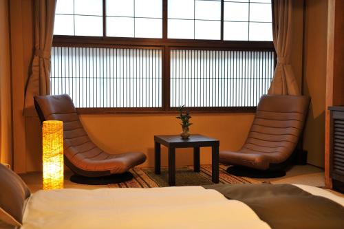 a bedroom with two chairs and a bed and a window at Hida Takayama Hodakaso Yamano Iori in Takayama
