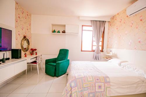 a bedroom with a large bed and a green chair at Casa em Campina Grande in Campina Grande