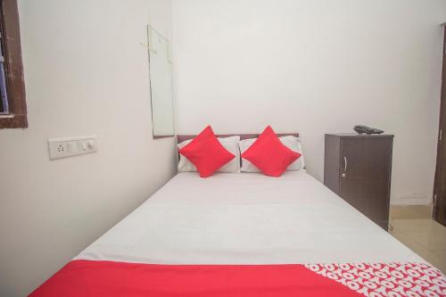 Habitación pequeña con cama con almohadas rojas en OYO Hotel Kshounish Residency, en Māldah