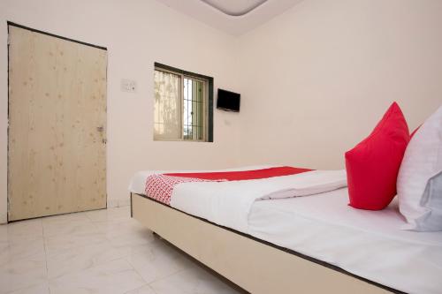 a bedroom with a bed with red pillows and a window at Hotel O Capital O Sai Icon Residency in Titwala