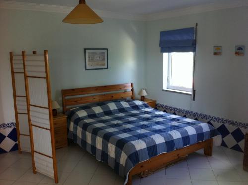 1 dormitorio con 1 cama con manta blanca y azul a cuadros en Apartamento Navegantes, en Sintra