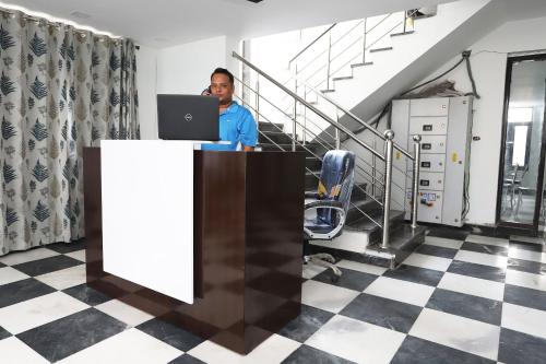 a man sitting at a desk with a laptop at Capital O Peaceful Stays Near ISKCON Temple Noida in Noida