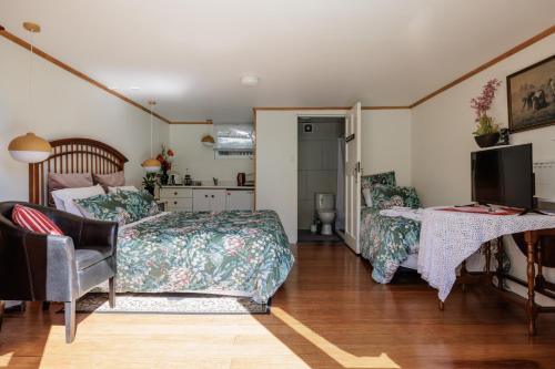a bedroom with two beds and a television and a desk at History @ Renall in Masterton