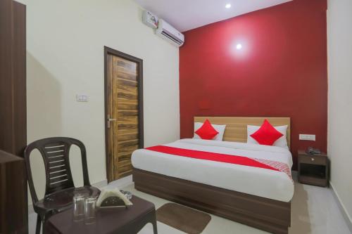 a bedroom with a bed with a red wall at OYO Sewa Residency in Faridabad