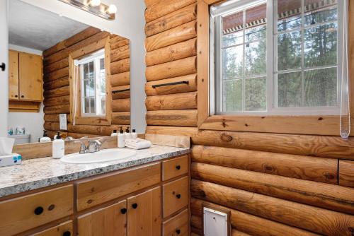 baño en una cabaña de madera con lavabo y ventana en Pine Loop Log Cabin, en La Pine