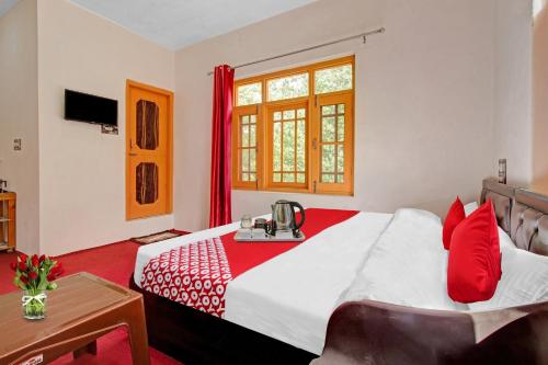 a bedroom with a large bed with red pillows at OYO Green Resort in Gandbal