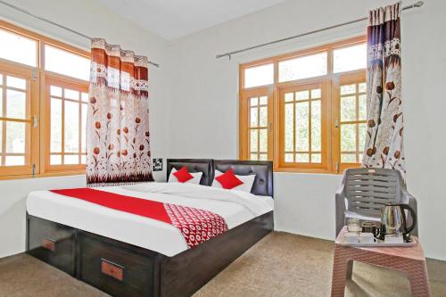 sypialnia z łóżkiem, stołem i oknami w obiekcie OYO Green Resort w mieście Gandbal